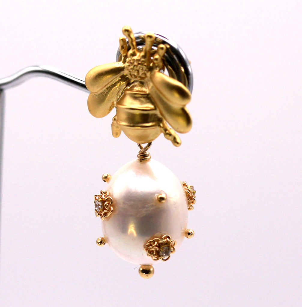 Genuine freshwater pearl earrings.  The 12 mm diameter white pearl is decorated with clear zircon gemstones. The pearl dangles below a gold plated sterling silver bumble bee post. Front view