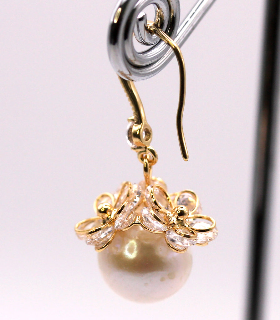 Women's Gold Plated Sterling Silver Earrings with Dangling 12 mm white round freshwater Pearls. The white pearl hangs at the bottom of a Sheppard hook set with zircon gemstones and a cluster of three crystal flowers. Side view