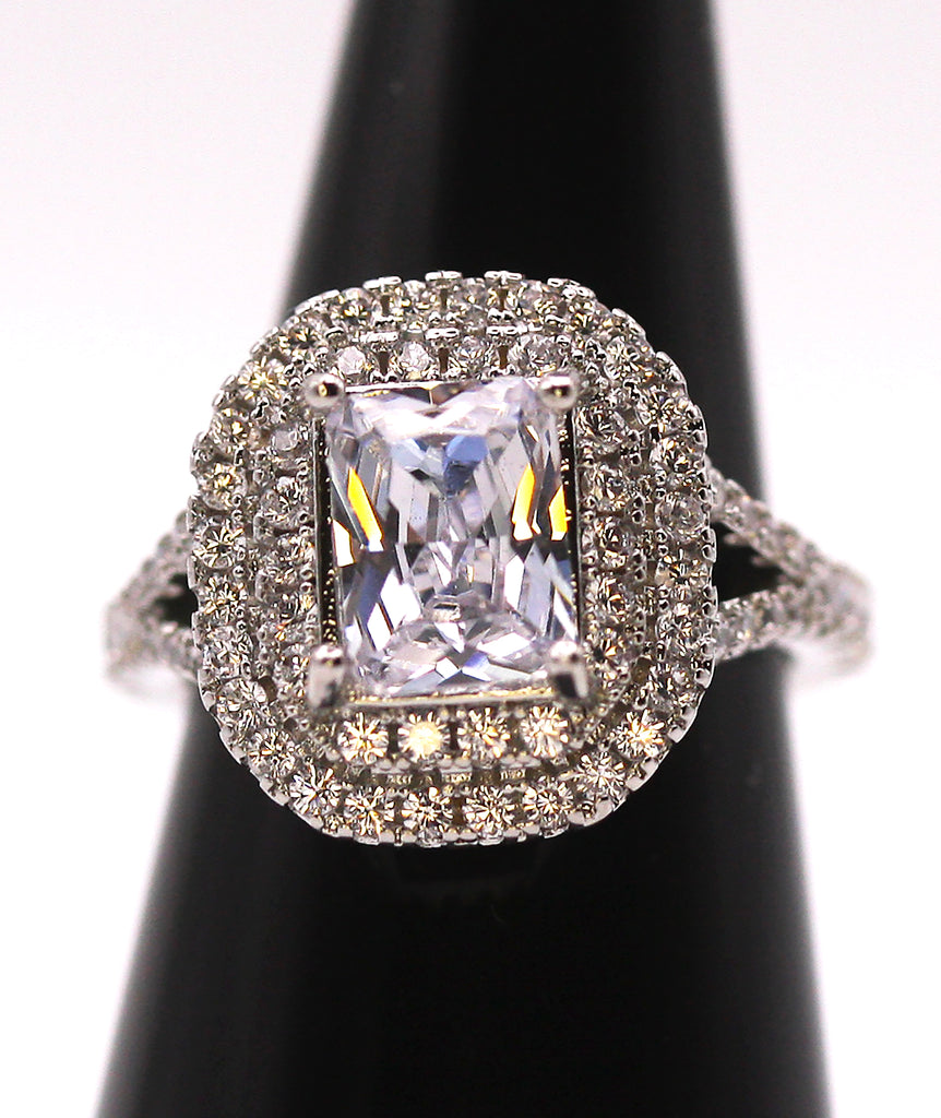 Women's Silver/Rhodium Plated Emerald Cut Solitaire Ring with Clear Zircon Gemstones. The solitaire is accented with two circles of pave set crystal stones on the face of the ring. The band is also accented with pave set zircons. 