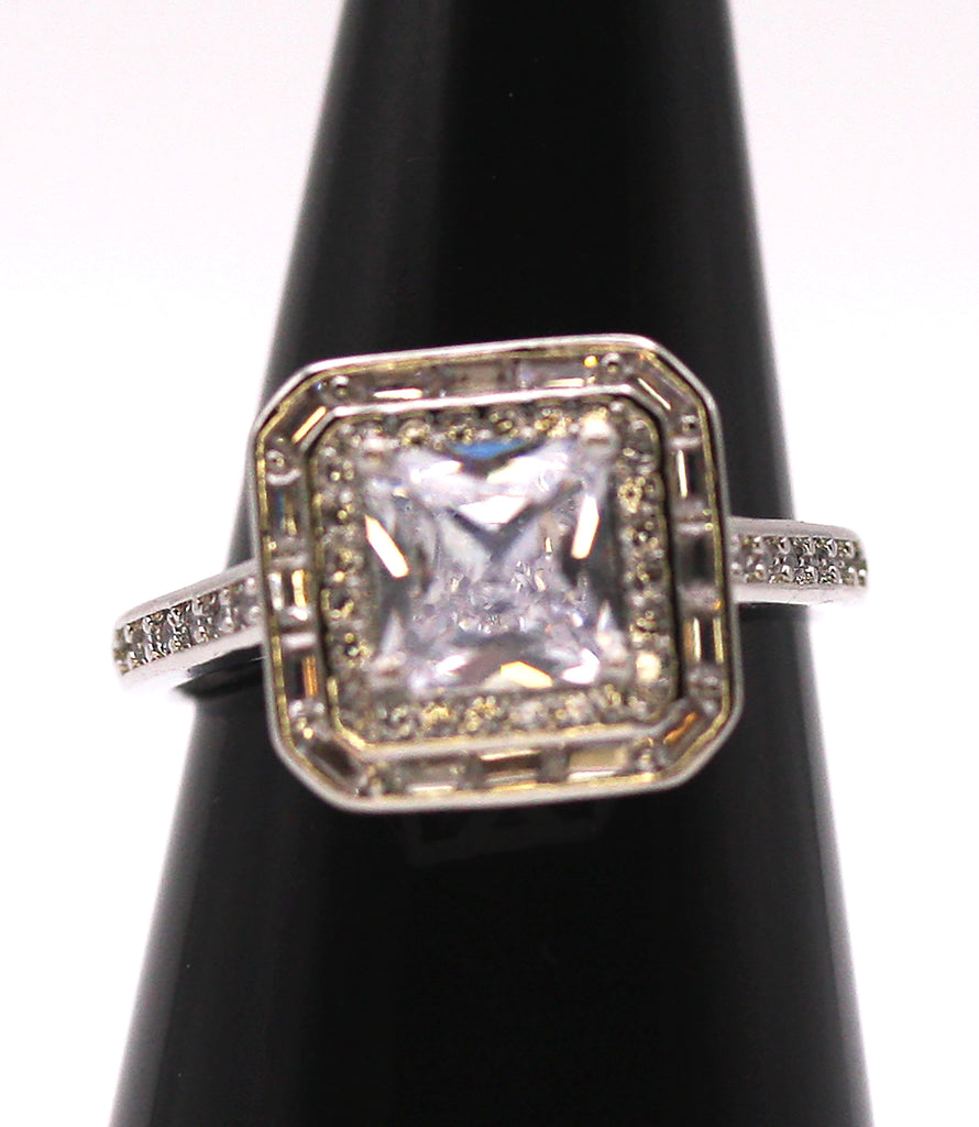 Women's Silver/Rhodium Plated Square Cut Solitaire Ring with Clear Zircon Gemstones. The solitaire is accented with one square of baguette cut crystals and on square of pave set crystal stones on the face of the ring. The band is also accented with pave set zircons. Front view