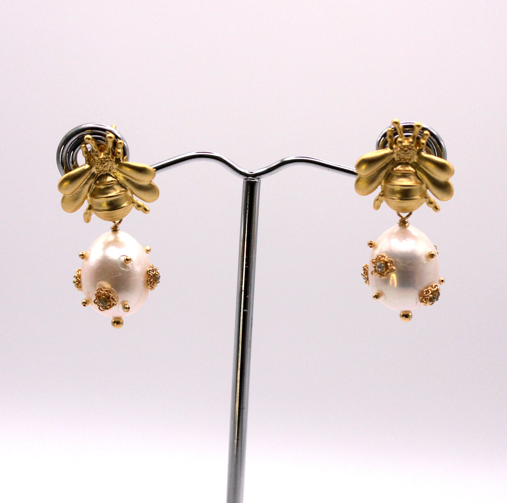 Genuine freshwater pearl earrings.  The 12 mm diameter white pearl is decorated with clear zircon gemstones. The pearl dangles below a gold plated sterling silver bumble bee post.