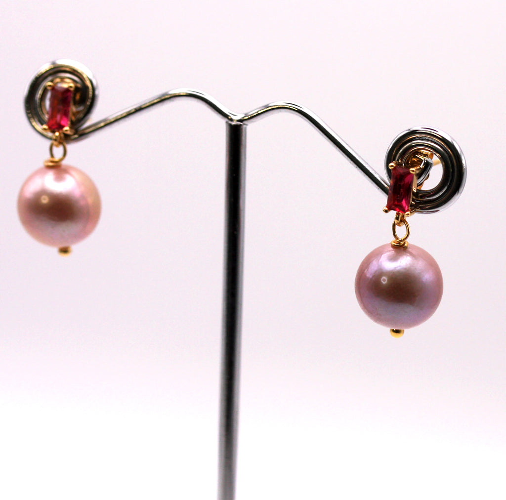 Women’s Dangling Earrings. Genuine freshwater pearl. Natural lavender colour. The pearl hand below a red baguette zircon gemstone. Top post in gold plated sterling silver.