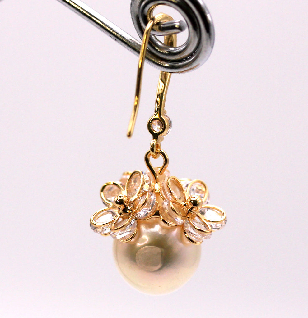 Women's Gold Plated Sterling Silver Earrings with Dangling 12 mm white round freshwater Pearls. The white pearl hangs at the bottom of a Sheppard hook set with zircon gemstones and a cluster of three crystal flowers. Back view