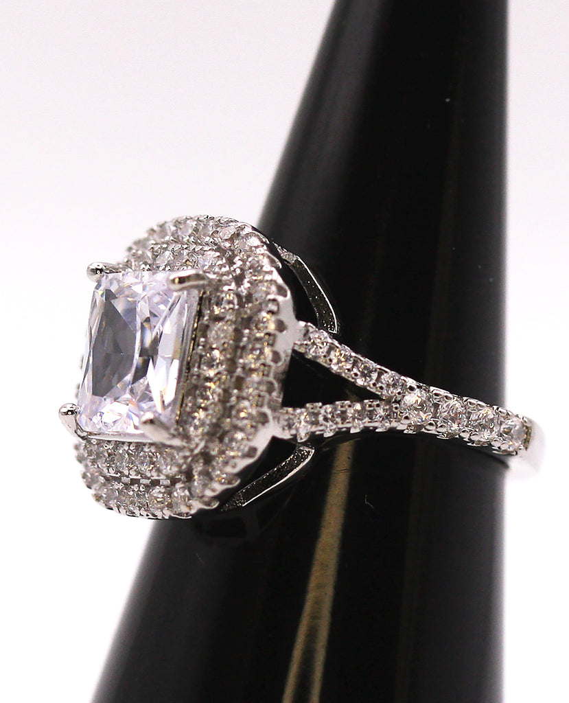 Women's Silver/Rhodium Plated Emerald Cut Solitaire Ring with Clear Zircon Gemstones. The solitaire is accented with two circles of pave set crystal stones on the face of the ring. The band is also accented with pave set zircons. Side view