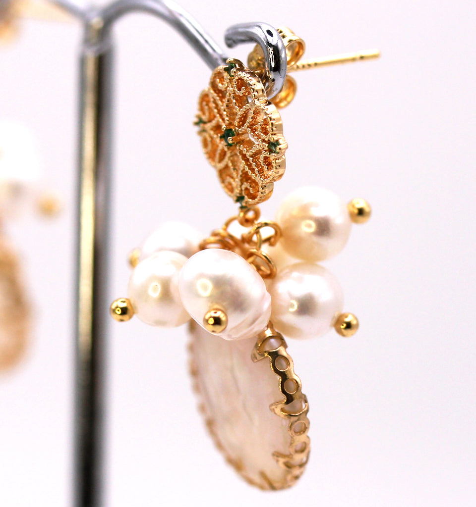 Women's Gold Plated Sterling Silver Earrings with Dangling 16 mm decorated Coin freshwater Pearls. The white pearl hangs at the bottom of a top post filigree flower set with five green zircon gemstones and a cluster of five 4 mm white pearls. Side view