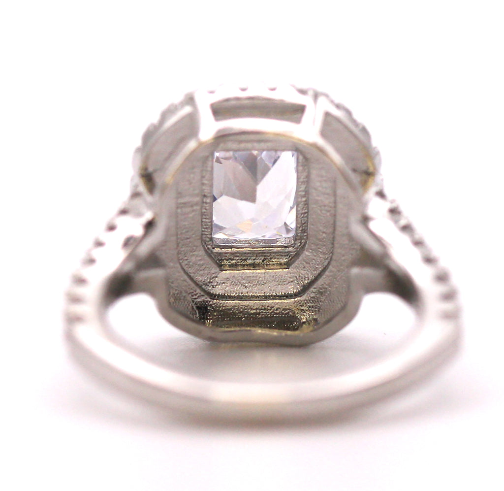Women's Silver/Rhodium Plated Emerald Cut Solitaire Ring with Clear Zircon Gemstones. The solitaire is accented with two circles of pave set crystal stones on the face of the ring. The band is also accented with pave set zircons. Back view