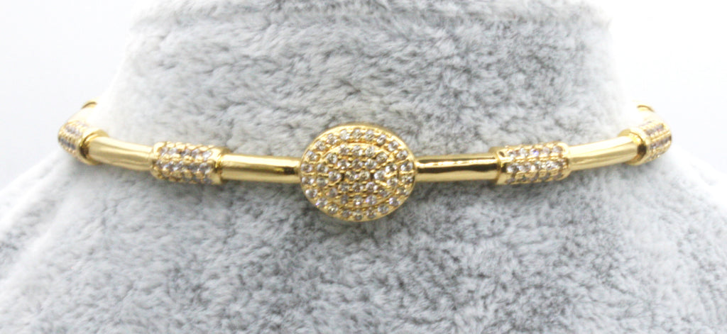 Women's open bangle bracelet. Yellow gold plated. Decorated with cylinders pave set clear zircon gemstones.