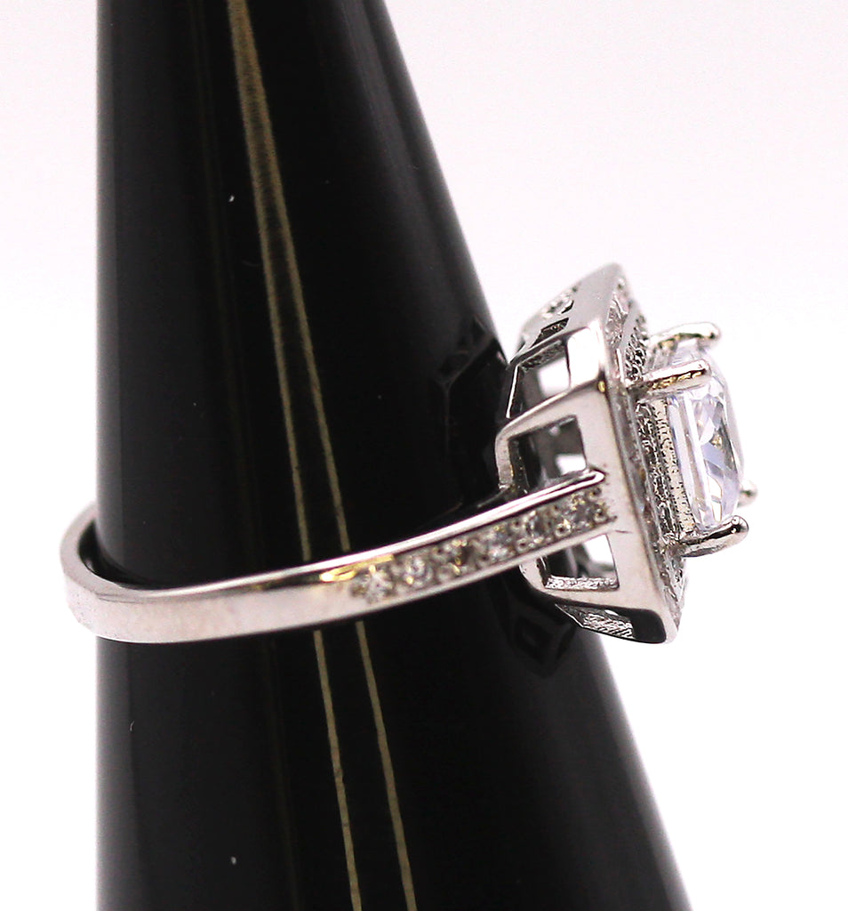 Women's Silver/Rhodium Plated Square Cut Solitaire Ring with Clear Zircon Gemstones. The solitaire is accented with one square of baguette cut crystals and on square of pave set crystal stones on the face of the ring. The band is also accented with pave set zircons. Side view