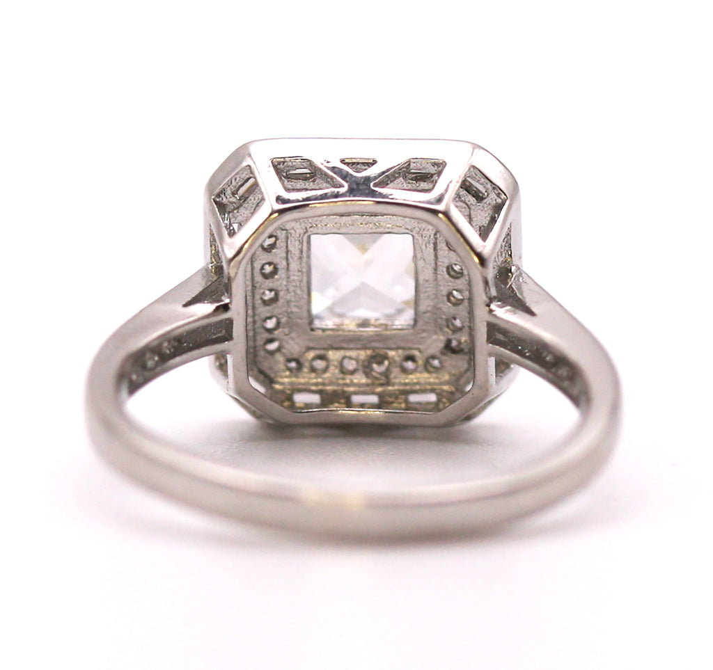 Women's Silver/Rhodium Plated Square Cut Solitaire Ring with Clear Zircon Gemstones. The solitaire is accented with one square of baguette cut crystals and on square of pave set crystal stones on the face of the ring. The band is also accented with pave set zircons. Back view