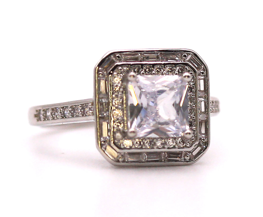 Women's Silver/Rhodium Plated Square Cut Solitaire Ring with Clear Zircon Gemstones. The solitaire is accented with one square of baguette cut crystals and on square of pave set crystal stones on the face of the ring. The band is also accented with pave set zircons. Face view