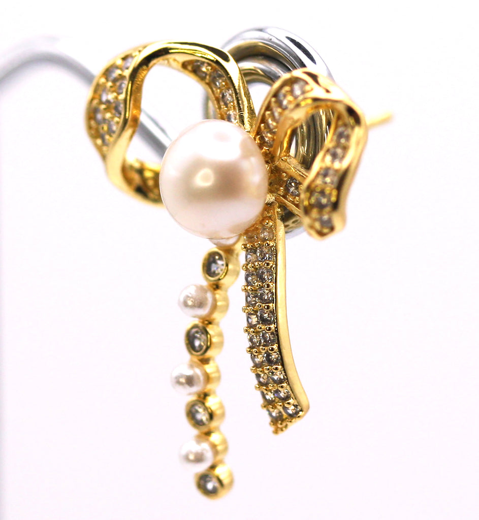 Women's Gold Plated Sterling Silver Earrings with freshwater Pearls. 6 mm white pearl in the centre of a bow ribbon pave set with clear zircon gemstones. Side view